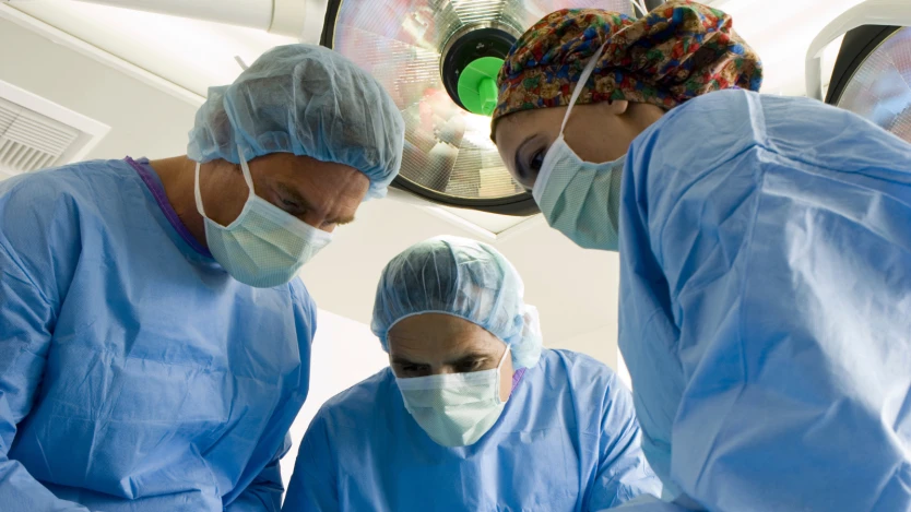 Trois chirurgiens portant un masque dans une salle d'opération