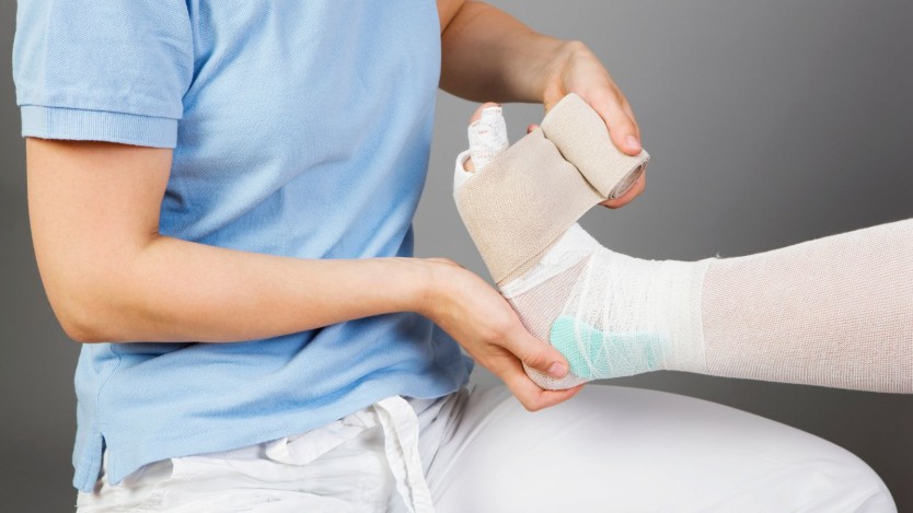 Jeune homme bandant le pied d'un patient